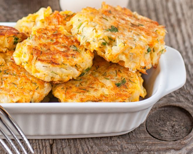 Healthy vegetarian cabbage patties with carrot and onion against the backdrop of sour cream sauce with herbs