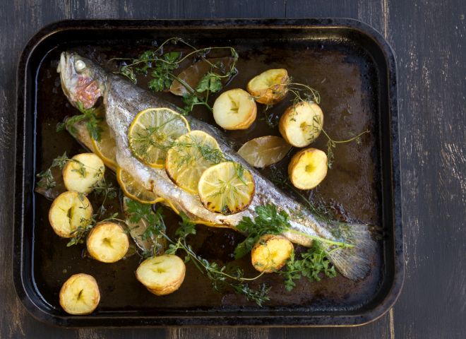 Delicious baked rainbow trout straight from the oven with potato, lemon and herbs.