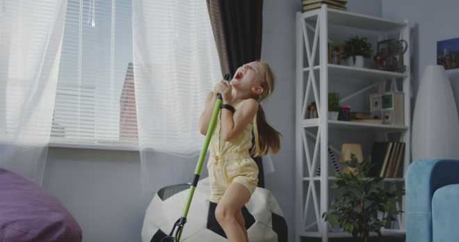 bambina canta e balla con la scopa mentre fa le pulizie